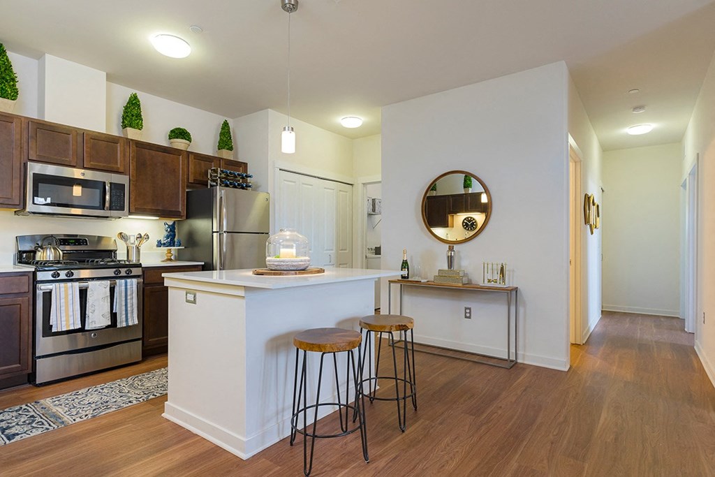 a kitchen with a white counter top and a bar with two stools
