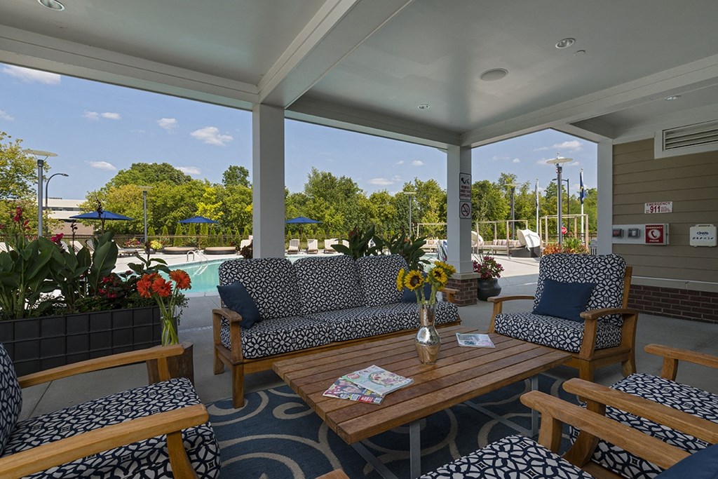 a covered porch with couches and a table with flowers