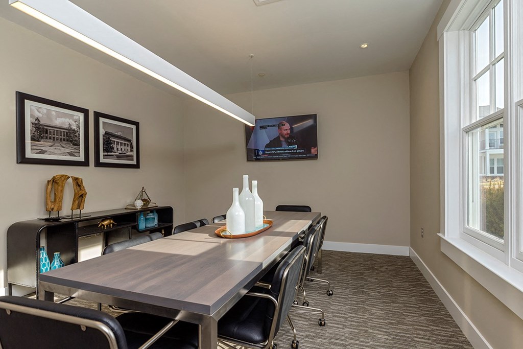 a conference room with a table and chairs and a television