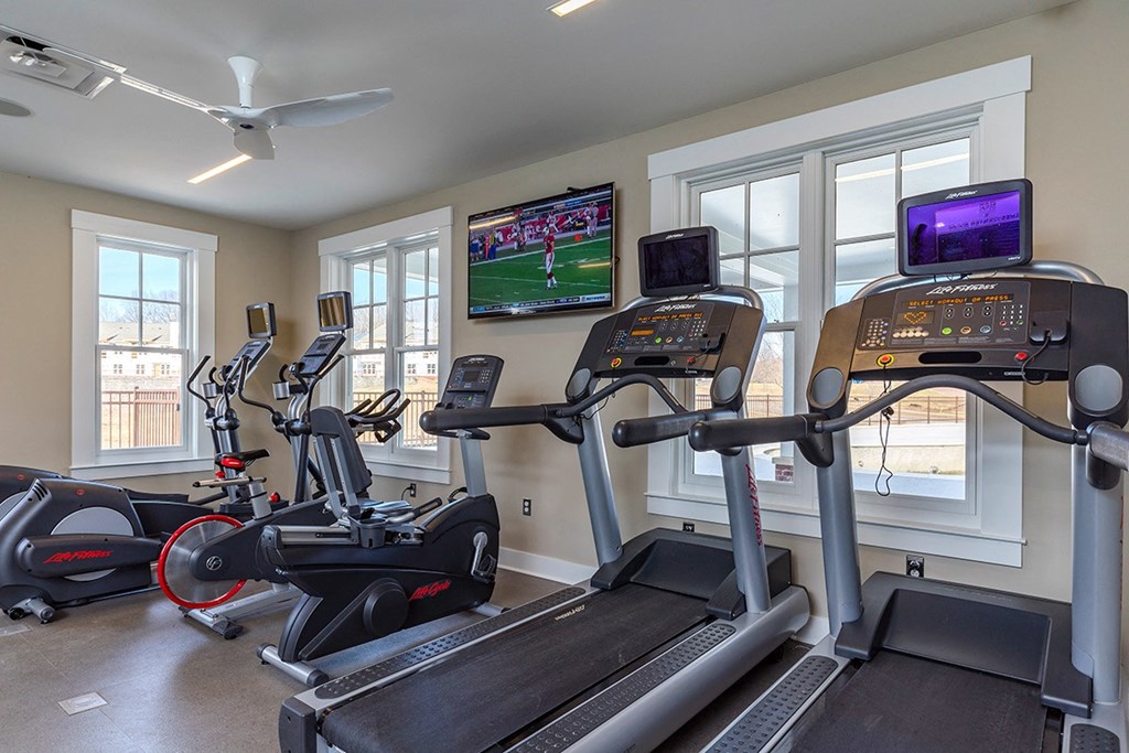 a gym with treadmills and televisions