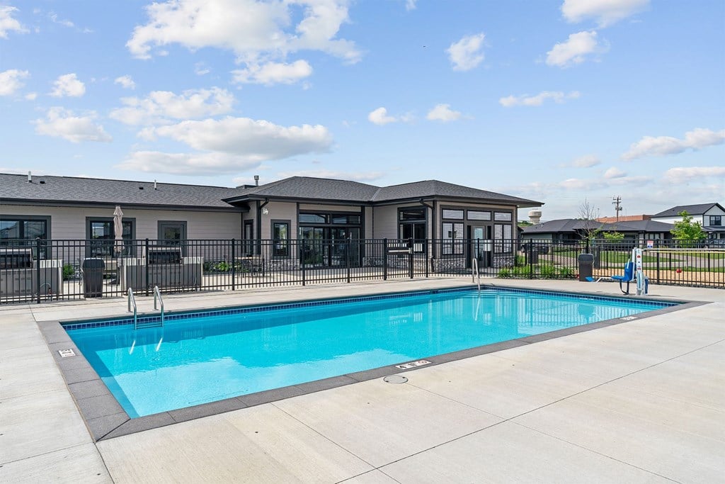 A swimming pool in front of a building with a person standing by the pool.