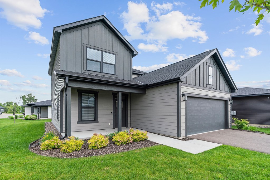 A modern house with a grey exterior and a large front yard.