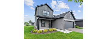 A modern house with a grey exterior and a large front yard.