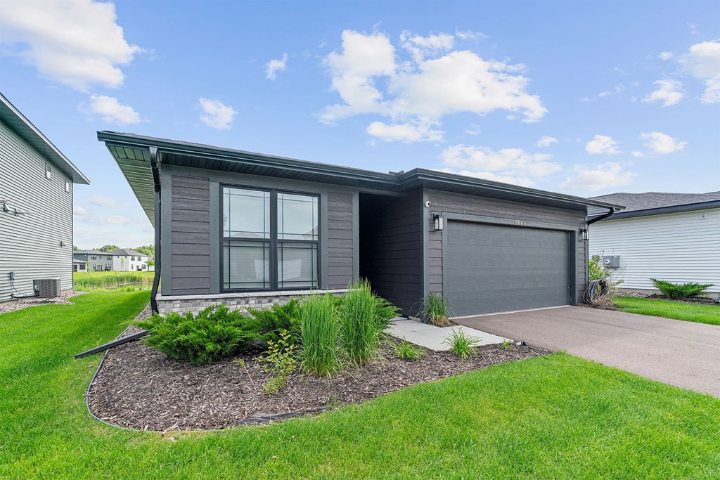 A modern house with a grey exterior and a landscaped front yard.