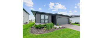 A modern house with a grey exterior and a landscaped front yard.