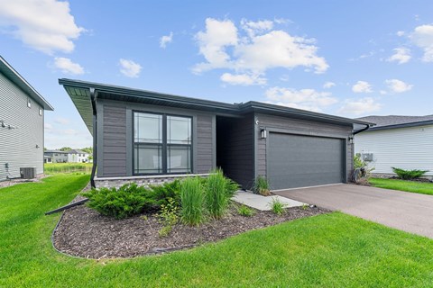 A modern house with a grey exterior and a landscaped front yard.