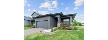 A modern house with a grey garage door and a stone pathway leading to it.