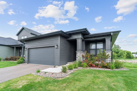 A modern house with a grey garage door and a stone pathway leading to it.