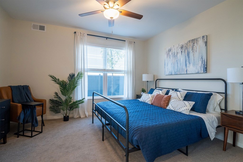 a bedroom with a bed and a ceiling fan and a window