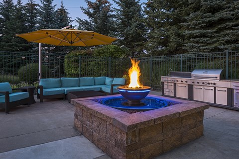 A fire burns in a blue bowl in the middle of a stone patio.