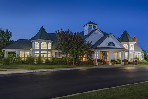 A large white house with a black roof and a tower is illuminated from the inside.
