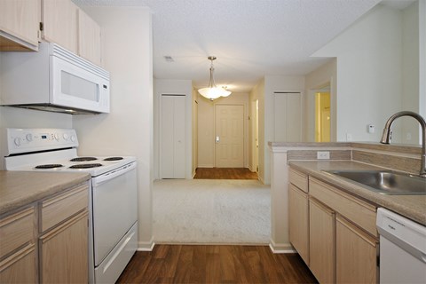 A kitchen with white appliances and wooden cabinets.