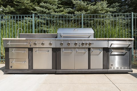 A large stainless steel outdoor grill with a side burner and a sink.