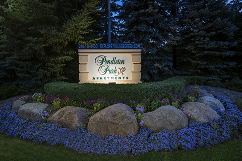 A sign for Pendleton Park Apartments is lit up at night.