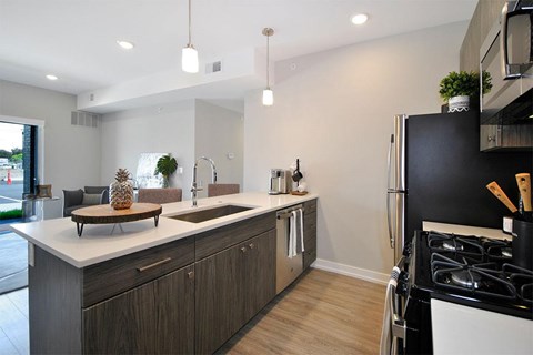 A modern kitchen with a black refrigerator and wooden cabinets.