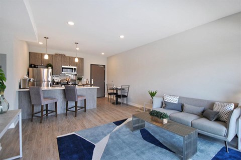 A modern living room with a kitchen in the background.