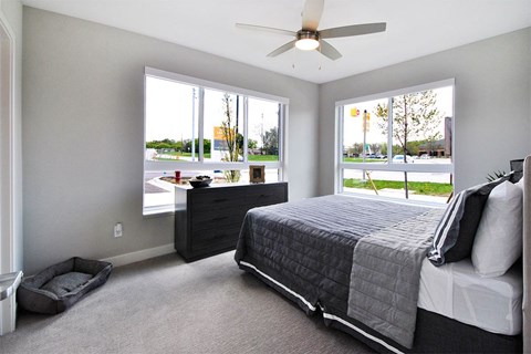 A bedroom with a bed, dresser, and a ceiling fan.