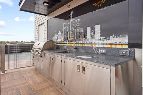 A kitchen with a stainless steel counter and cabinets with a Phoenix logo on the wall.
