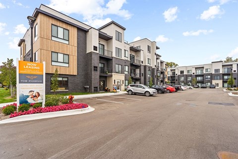 A parking lot in front of a building with a sign that says "Now Leasing".