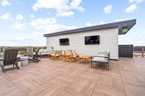 A wooden deck with chairs and a table in front of a house.
