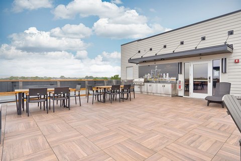 A patio with wooden tables and chairs is in front of a building.