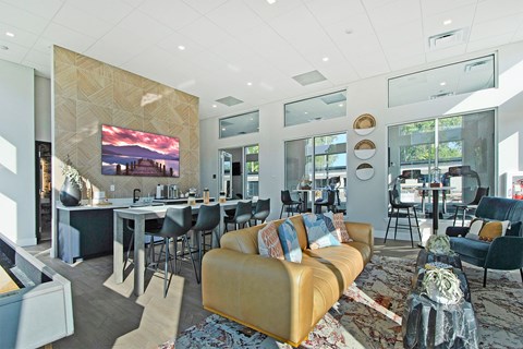 A modern living room with a yellow sofa and a large screen on the wall.
