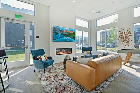 A living room with a blue chair, a brown couch, and a painting on the wall.