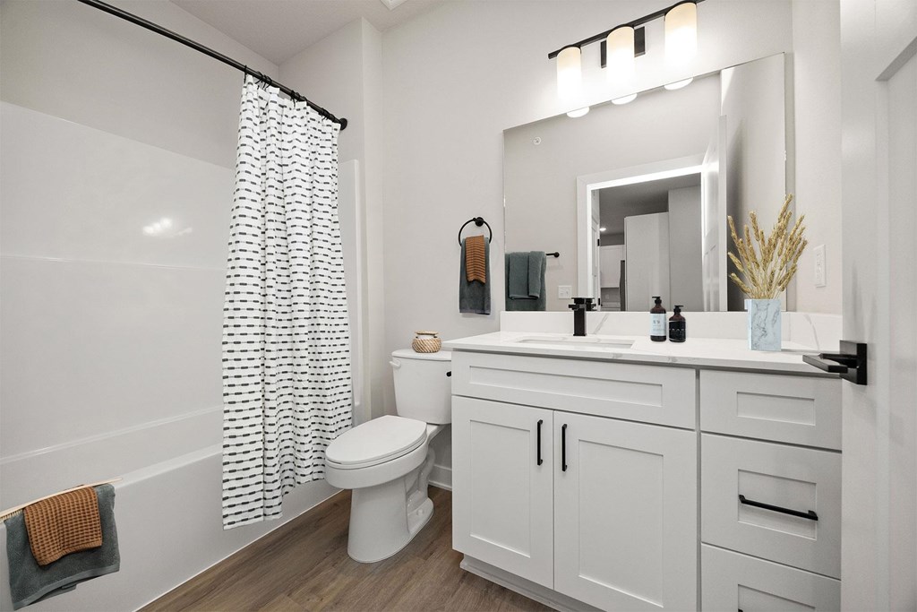 A white bathroom with a toilet, sink, and shower curtain.