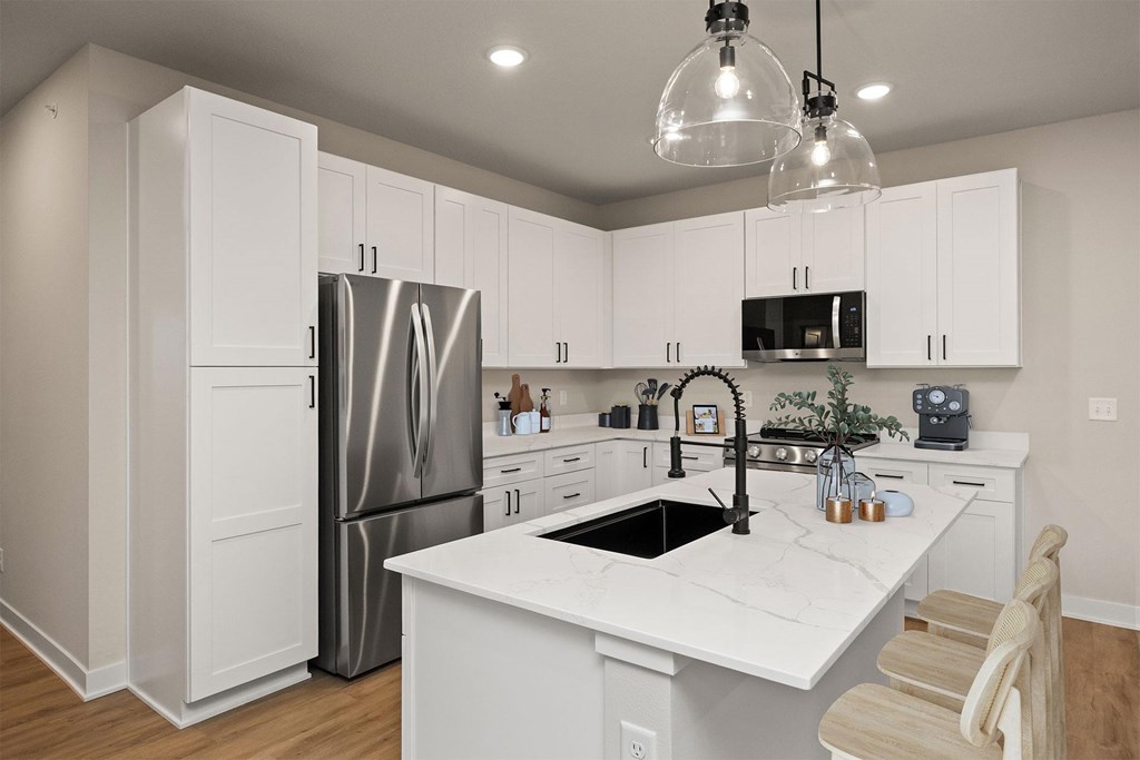 A kitchen with white cabinets and a marble countertop.