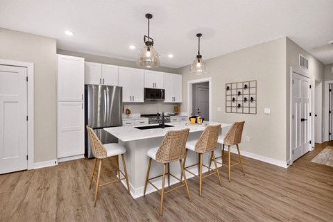 A kitchen with a white island and chairs.