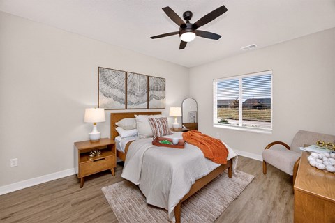 A bedroom with a bed, nightstand, and chair.