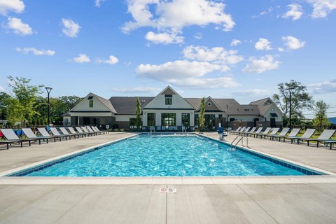 A large swimming pool with lounge chairs and a building in the background.