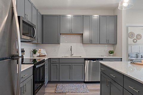 A kitchen with grey cabinets and a white countertop.