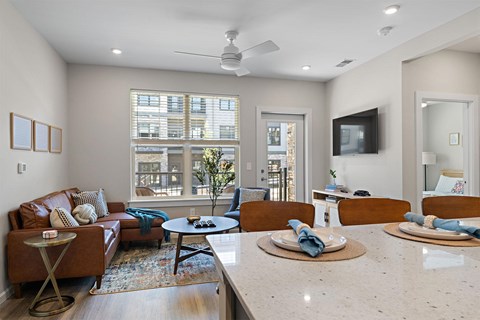 A living room with a brown leather couch and a white ceiling fan.