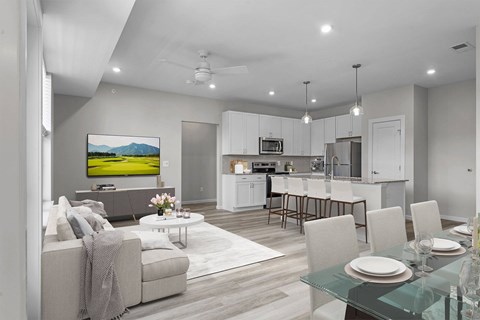 A modern living room with a grey couch and a glass dining table.