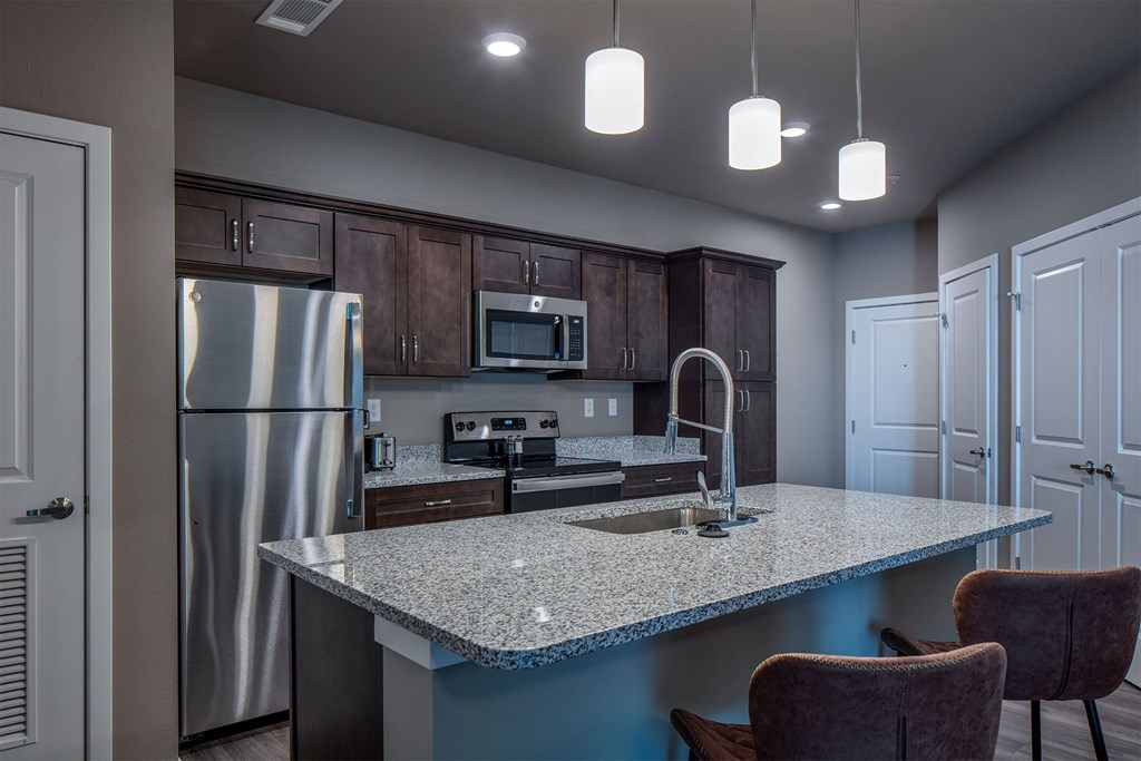 A kitchen with a refrigerator, microwave, and oven.