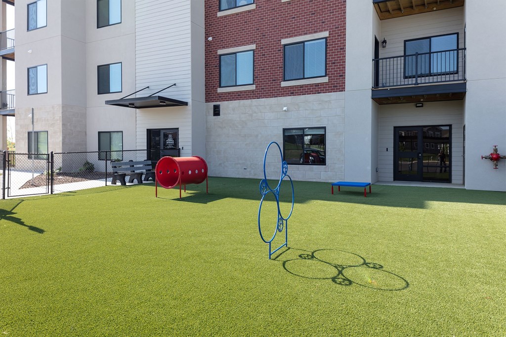 A playground with a red and blue swing set and a green lawn.