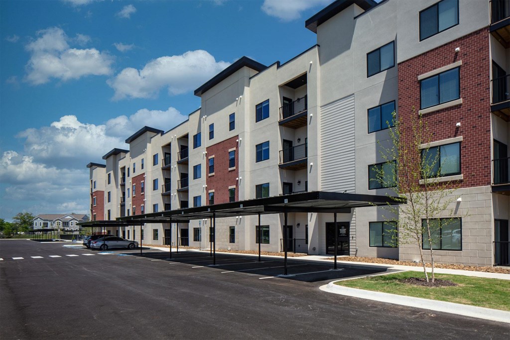 Apartment building with a parking lot in front.
