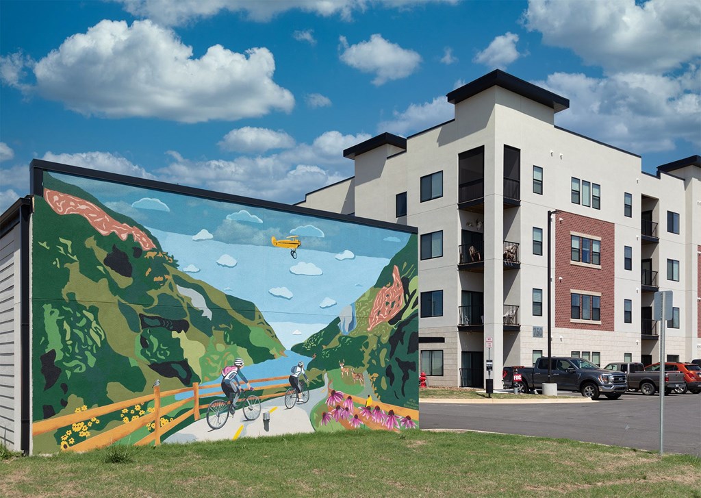 A mural of a person riding a bike is painted on the side of a building.