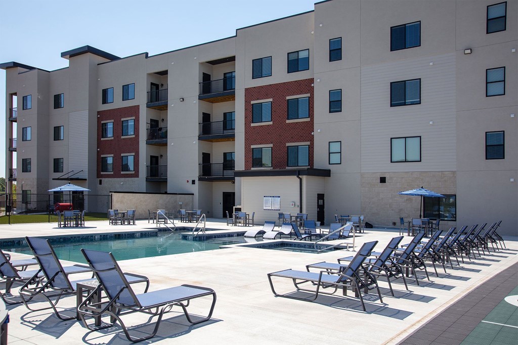 A pool area with chairs and a building in the background.