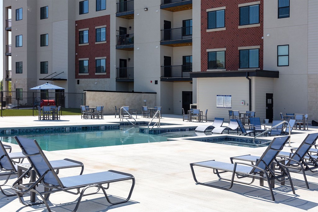 A pool area with chairs and a building in the background.