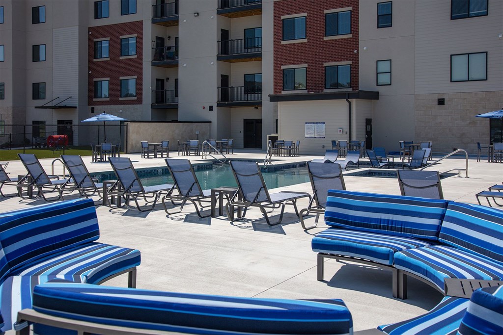 A sunny day at the outdoor seating area of a building with blue and white striped benches.
