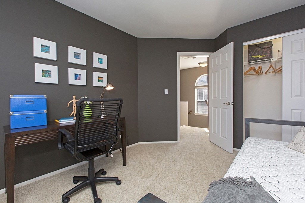 a bedroom with a desk and a bed and a closet