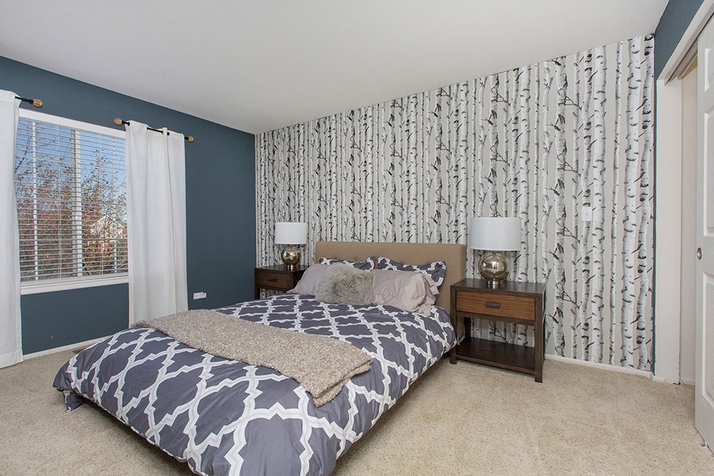 a bedroom with a bed and two nightstands and a blue and white wallpaper