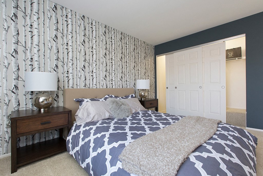 a bedroom with a bed with blue and white bedding and a gray and white