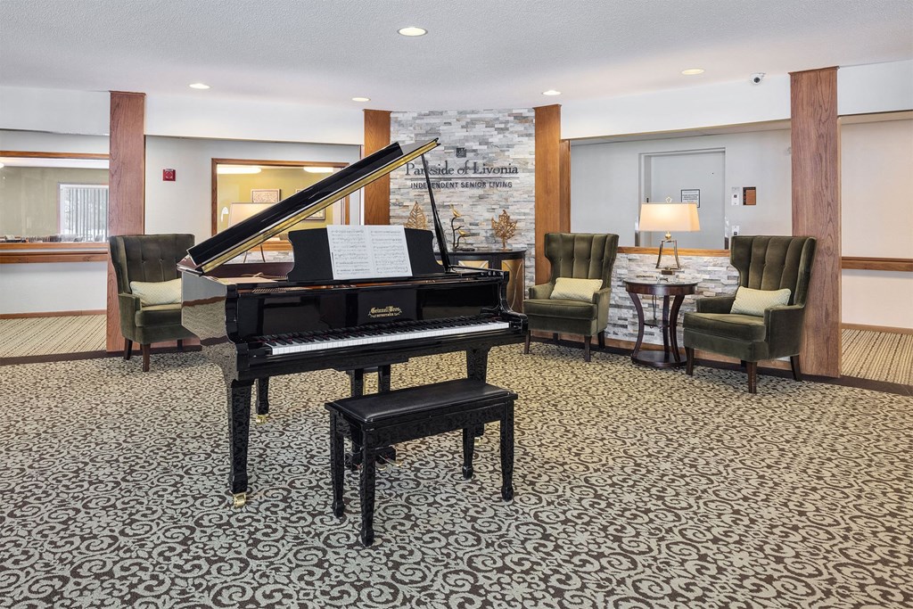 a piano in a lobby with chairs and a table