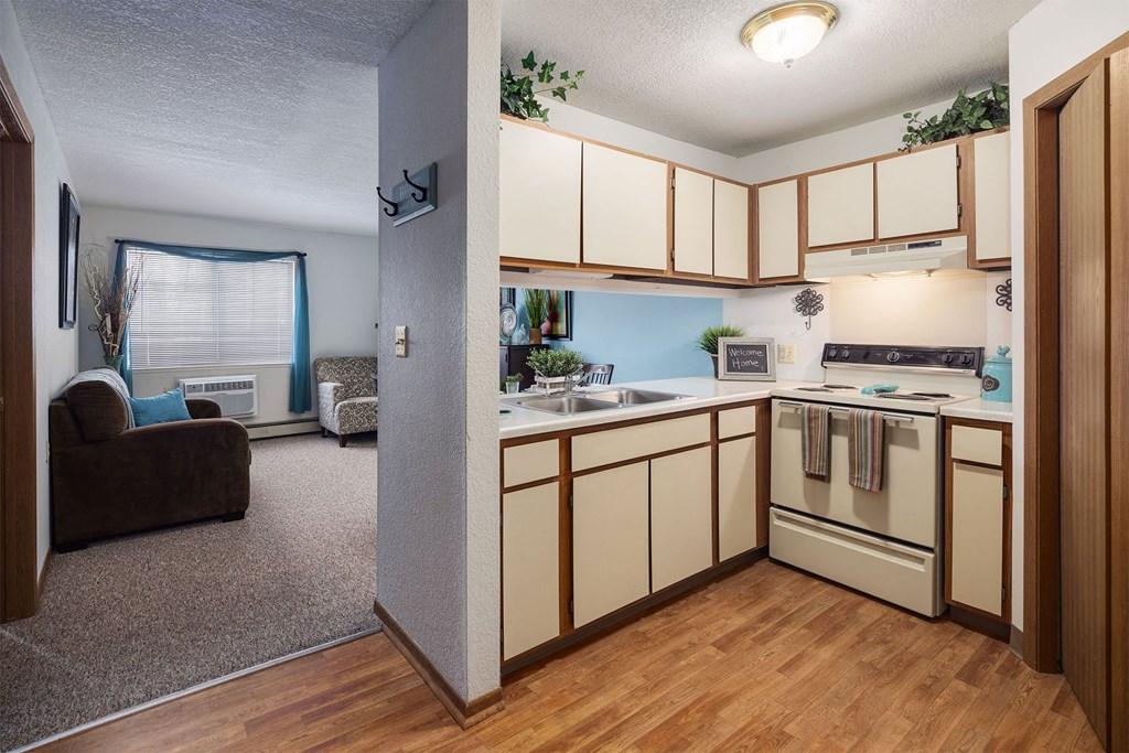 an open kitchen with white cabinets and appliances and a living room