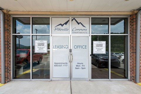 The image shows the entrance to the Pineville Commons Apartments leasing office.