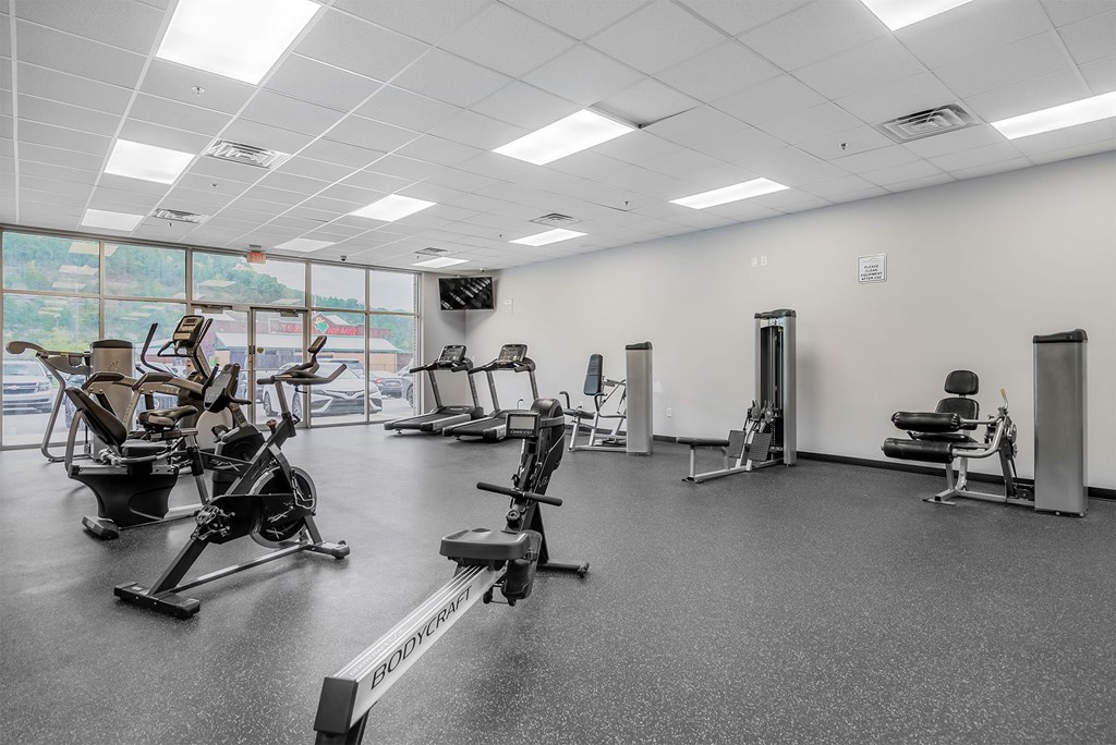 A gym with a variety of exercise equipment including treadmills, stationary bikes, and weight machines.
