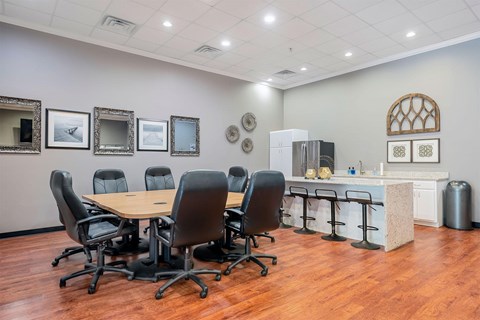 A conference room with a table surrounded by chairs and a whiteboard.